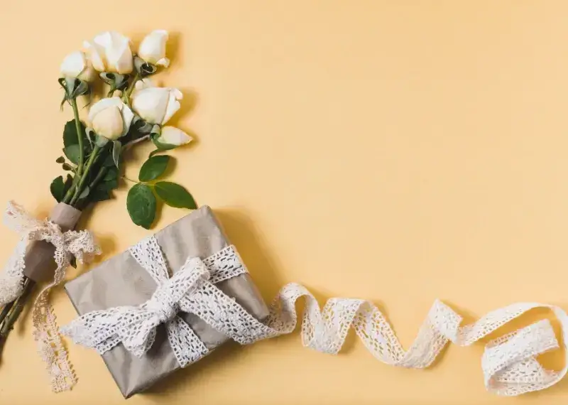 A beautifully wrapped birthday gift box with flowers and gold ribbon on a marble background